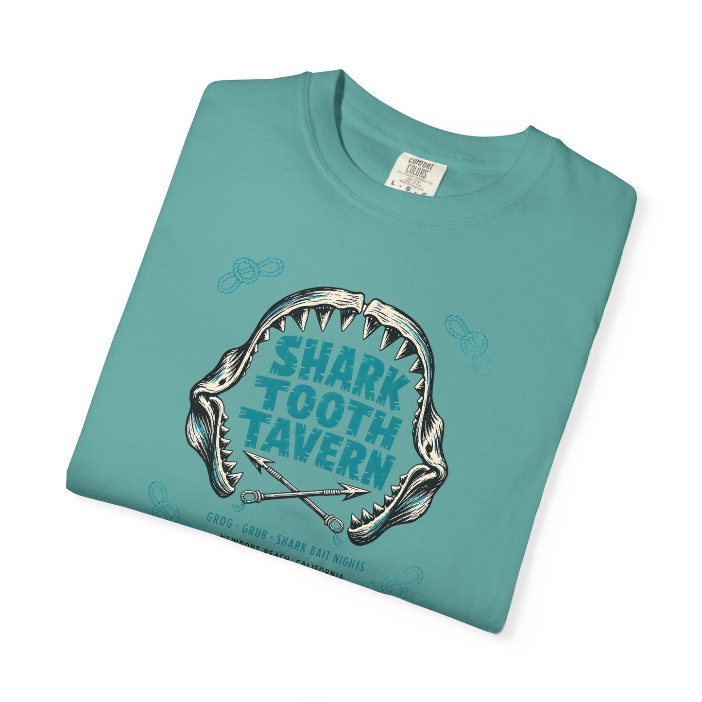 "Shark Tooth Tavern" — Newport Beach, California. Two inks, black and turquoise: a stylized shark-jaw arc with jagged carved teeth framing the venue name in bold tiki-block lettering, crossed harpoons...