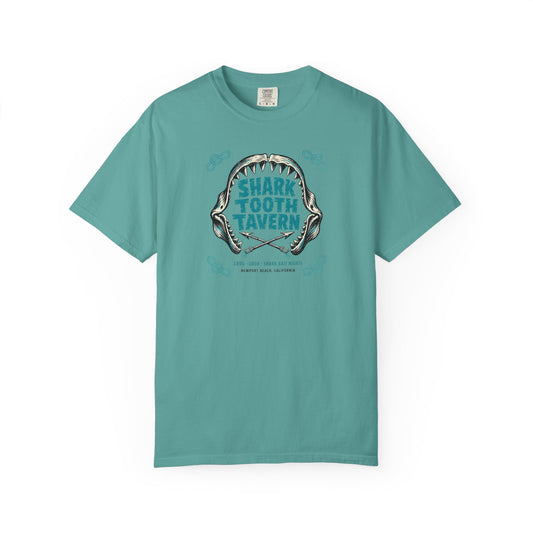 "Shark Tooth Tavern" — Newport Beach, California. Two inks, black and turquoise: a stylized shark-jaw arc with jagged carved teeth framing the venue name in bold tiki-block lettering, crossed harpoons...